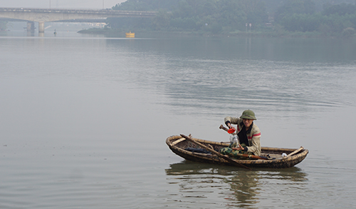 Sau khi nhận tiền, người đàn ông chèo con thuyền thúng ra gần giữa sông thả cá. Ảnh: Lam Sơn.