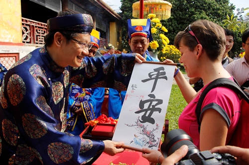 Du khách tham quan Hoàng cung Huế thích thú khi được nhận chữ. Ảnh: Võ Thạnh