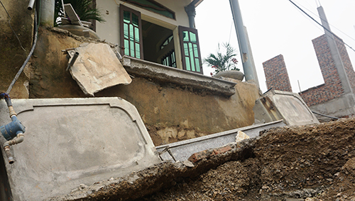 Một bức tường bị sập, đường ống nước sạch cũng đứt gãy sau hiện tượng sụt lún. Ảnh: Lam Sơn.