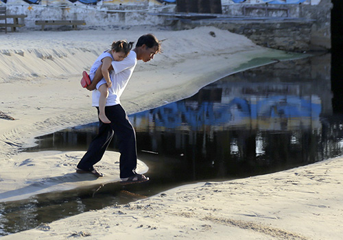 Người dân đi qua bờ biển ở Đà Nẵng bị nước thải chảy tràn qua. Ảnh: Nguyễn Đông.