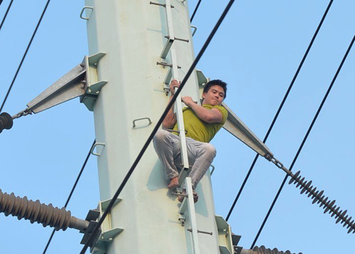 Nam thanh niên leo lên cột điện cao thế trên đường Tố Hữu và cố thủ suốt 3 giờ đồng hồ. ảnh: Tất Định