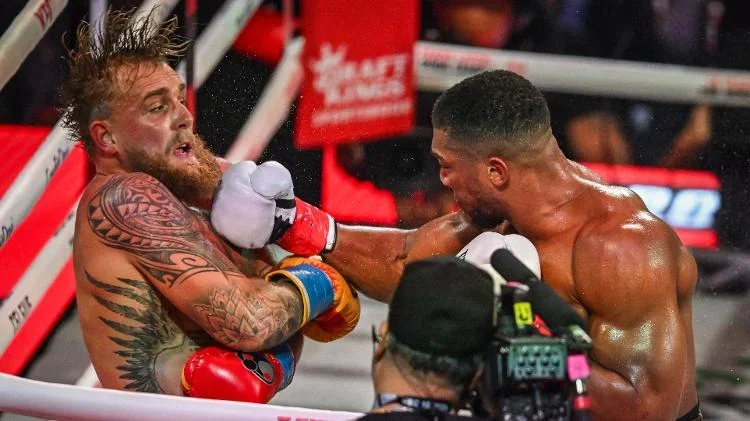 O boxeador e influenciador norte-americano Jake Paul (E) e o boxeador britânico Anthony Joshua lutam em um combate de peso-pesado sem disputa de título no Kaseya Center em Miami, Flórida